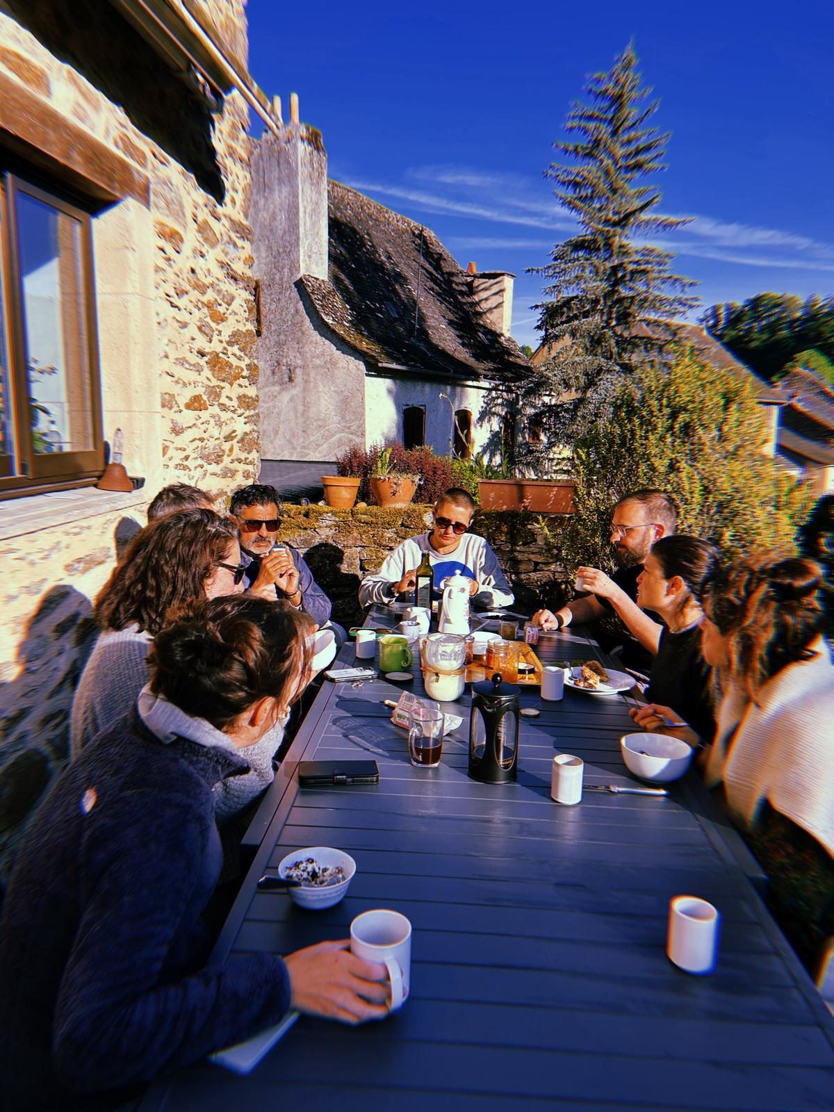 Petit-déjeuner du groupe en terrasse, devant une maison en pierre