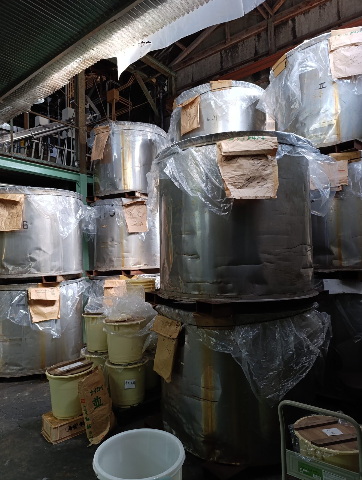 Grandes cuves de fermentation métalliques empilées sur trois niveaux sous une charpente en bois