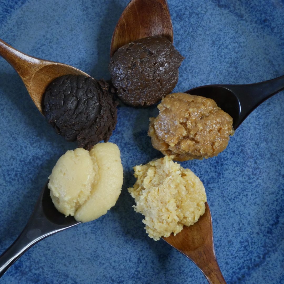 Cinq pâtes de miso de couleurs différentes présentées sur des cuillères